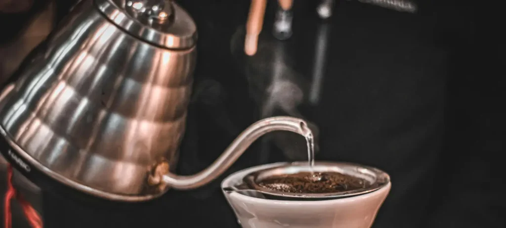 How to Use a Gooseneck Kettle Like a Pro ☕✨ 34 Person pouring hot water from a gooseneck kettle over coffee grounds during pour-over brewing