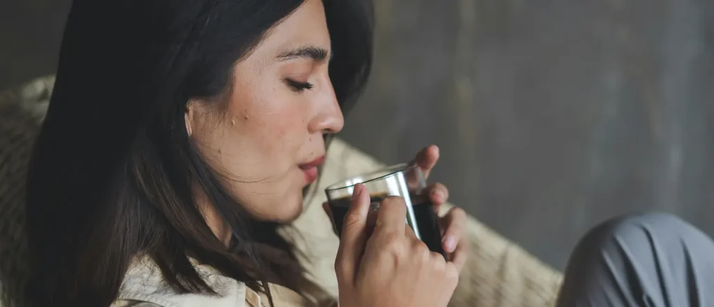 How to Quit Caffeine Now (Without Feeling Miserable) ☕➡️🌿 24 Woman relaxing on a lounge while drinking coffee during a caffeine reduction lifestyle routine