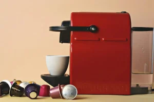 Pods for Nespresso: A Guide to Better Coffee at Home ☕✨ 4 Side view of a Nespresso-style coffee machine making a cup of coffee using pods. On the bench are the coffee pods for Nespresso machine