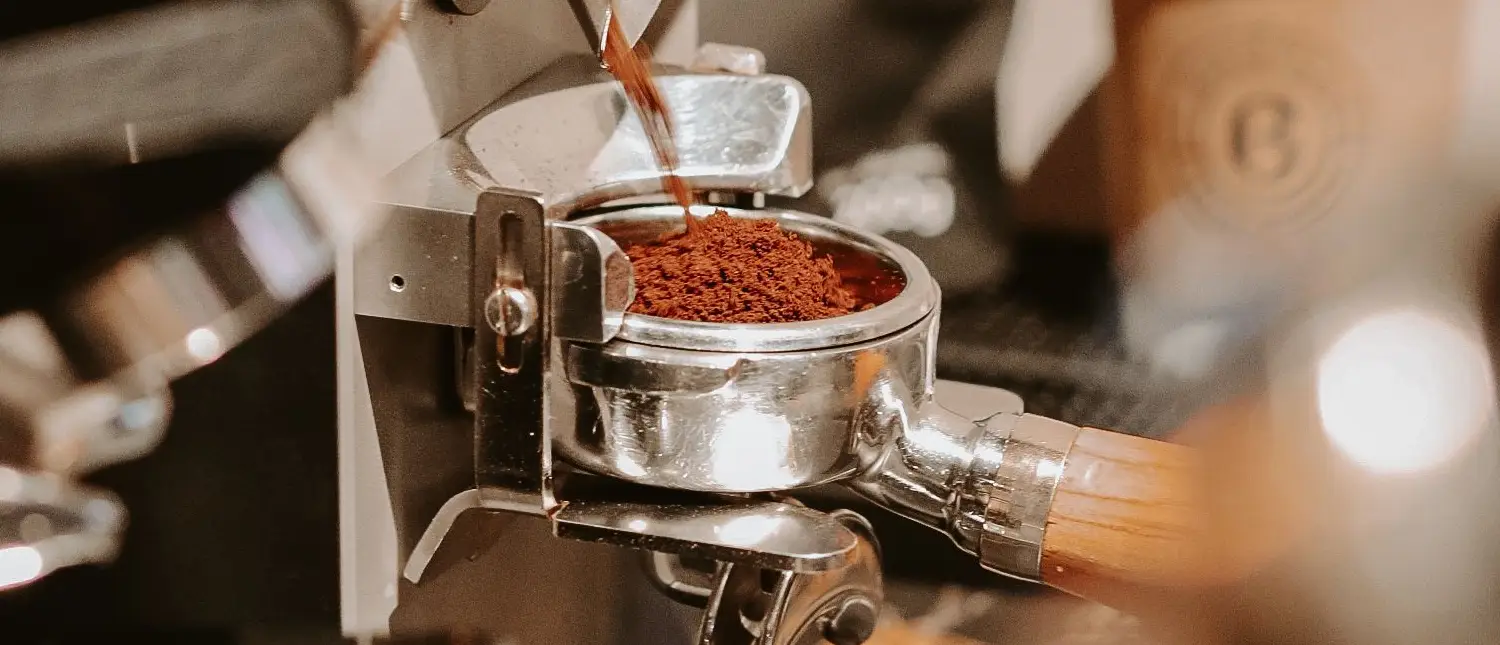 How Coffee Grind Size Affects Flavor: Complete Guide 2 Freshly ground coffee in a portafilter ready to be inserted into an espresso machine, demonstrating how grind size affects coffee flavor and extraction.