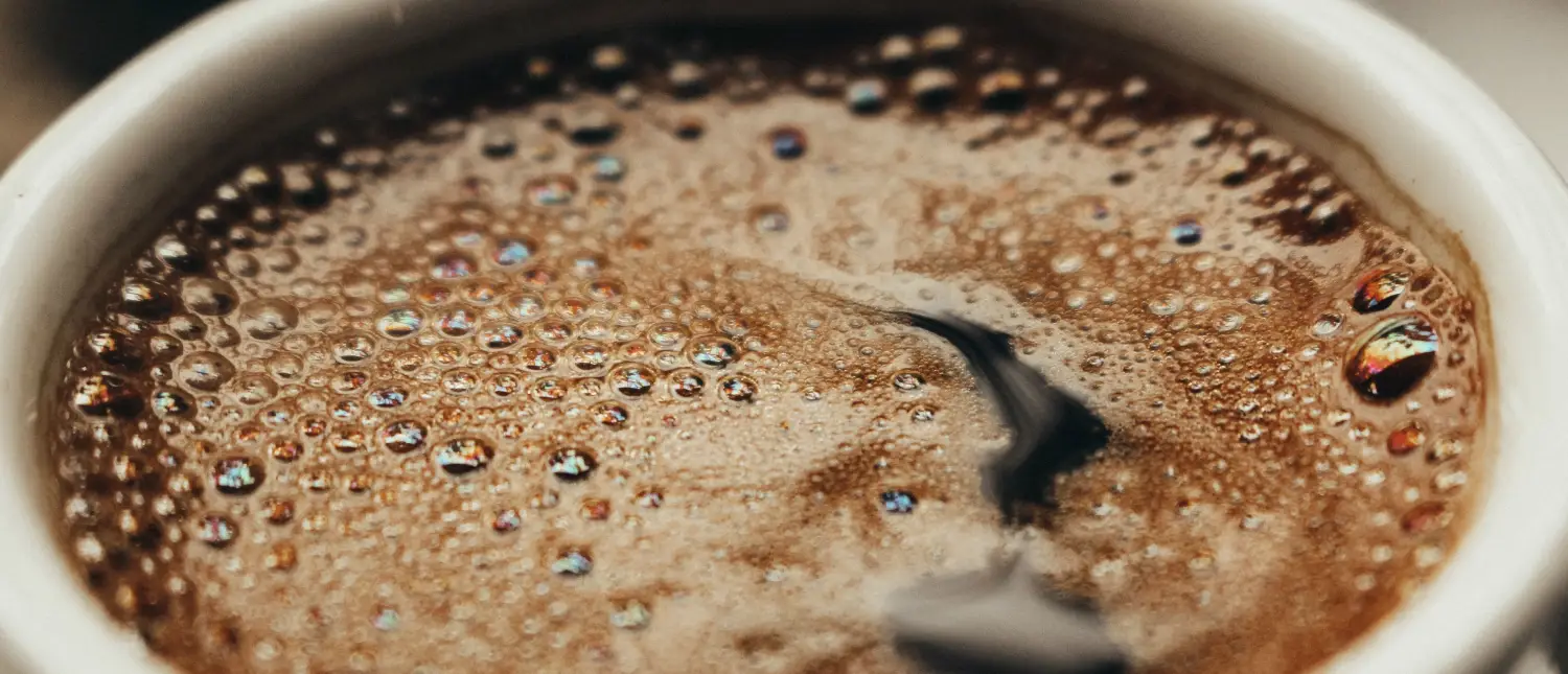 Exactly How Much Caffeine Is in 3 Shots of Espresso? 2 Top view of a cup of black coffee showing the dark surface of the drink while discussing whether a triple shot espresso contains too much caffeine.