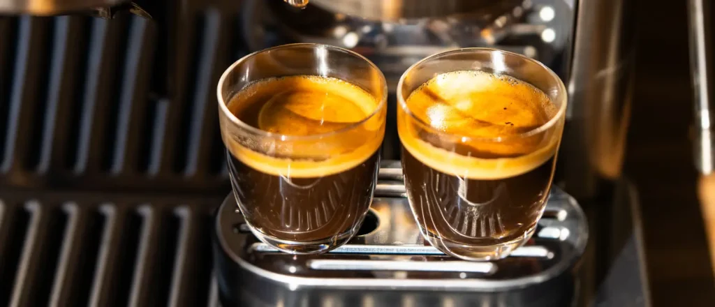 Single Shot vs Double Shot Espresso: Which One Should You Choose? ☕✨ 18 Single Shot vs Double Shot Espresso -Two freshly brewed espresso shots pouring from an espresso machine into glass cups.