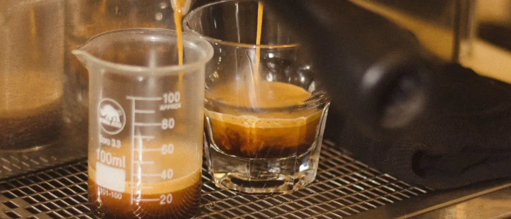 Triple Shot vs Double Shot Espresso: What's the Difference? 16 Two espresso shots being poured from an espresso machine during a comparison of triple shot vs double shot espresso.