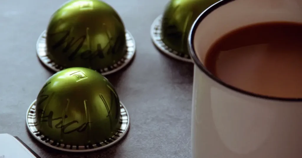 Nespresso Vertuo Capsules Ranked (2026) 7 Cup of freshly brewed Nespresso coffee with Vertuo capsules arranged on a table