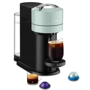 Nespresso Vertuo Next Review (2026) Nespresso Vertuo Next coffee machine brewing coffee on a kitchen bench with a Vertuo capsule beside it